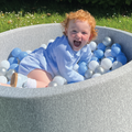 A young boy playing in the blue ball pit for babies.