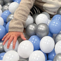 A baby reaching for balls that lie inside the Blue Ball Pit by Nuby.