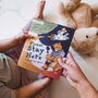 A child holding a book alongside their parent.