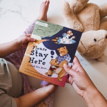 A child holding a book alongside their parent.