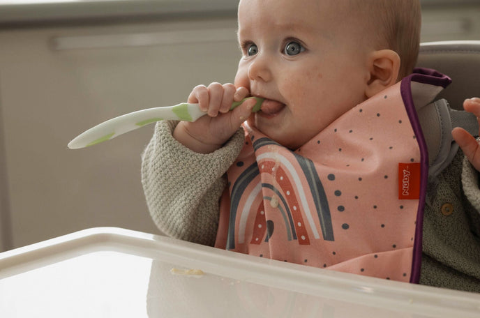 A baby chewing on a Nuby spoon while teething.