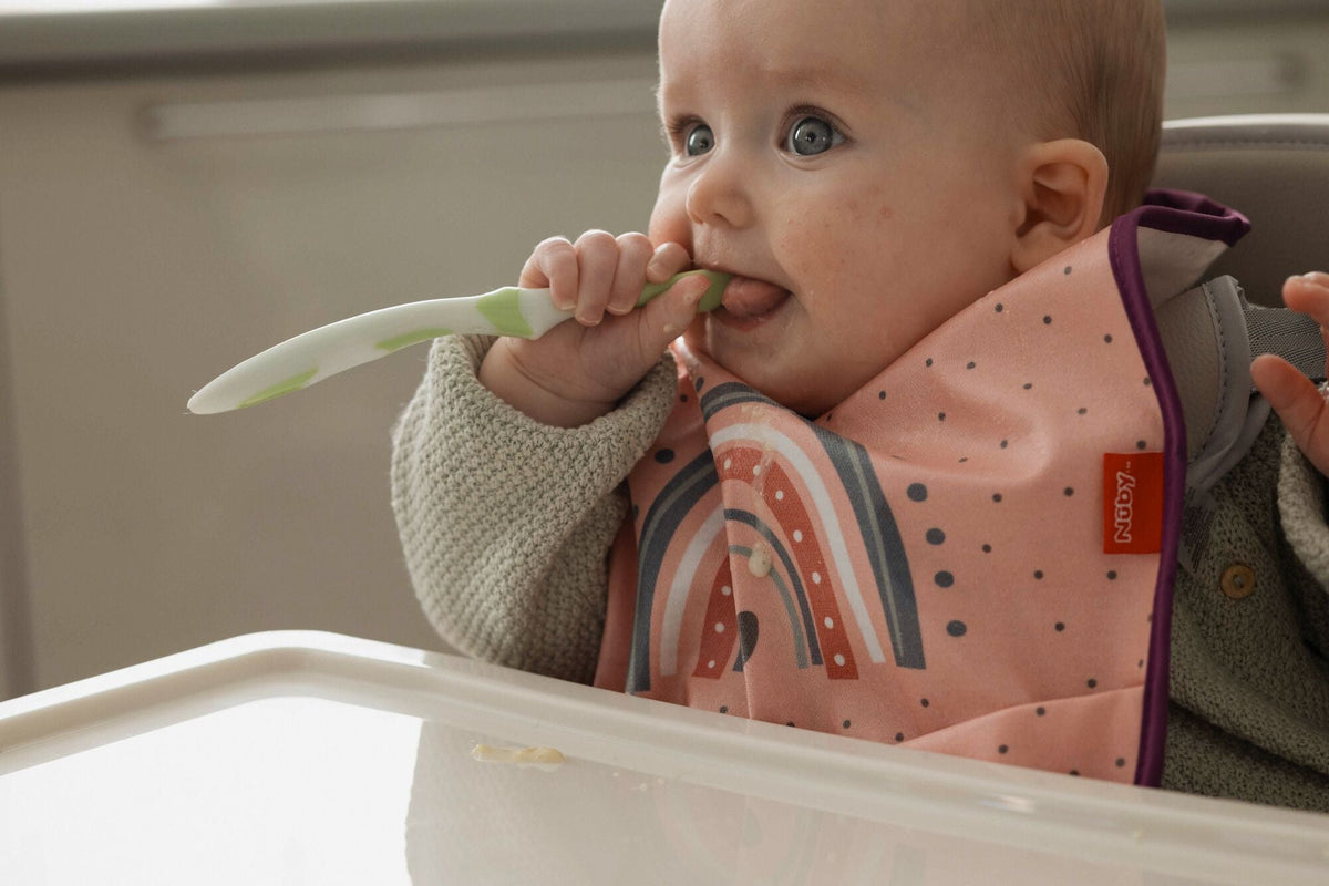 A baby chewing on a Nuby spoon while teething.
