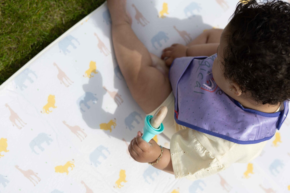 A baby holding a Nuby weaning apparatus.