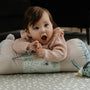 A close up of a baby playing on a Tummy Time Pillow created by Nuby.
