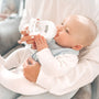 A baby drinking from a Nuby bottle while in their parents' arms.