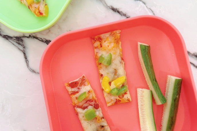 An overhead image of the Tortilla pizzas created and placed on red and green plates.