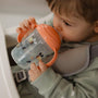 A baby holding a bee decorated sippy cup to their mouth to drink from.