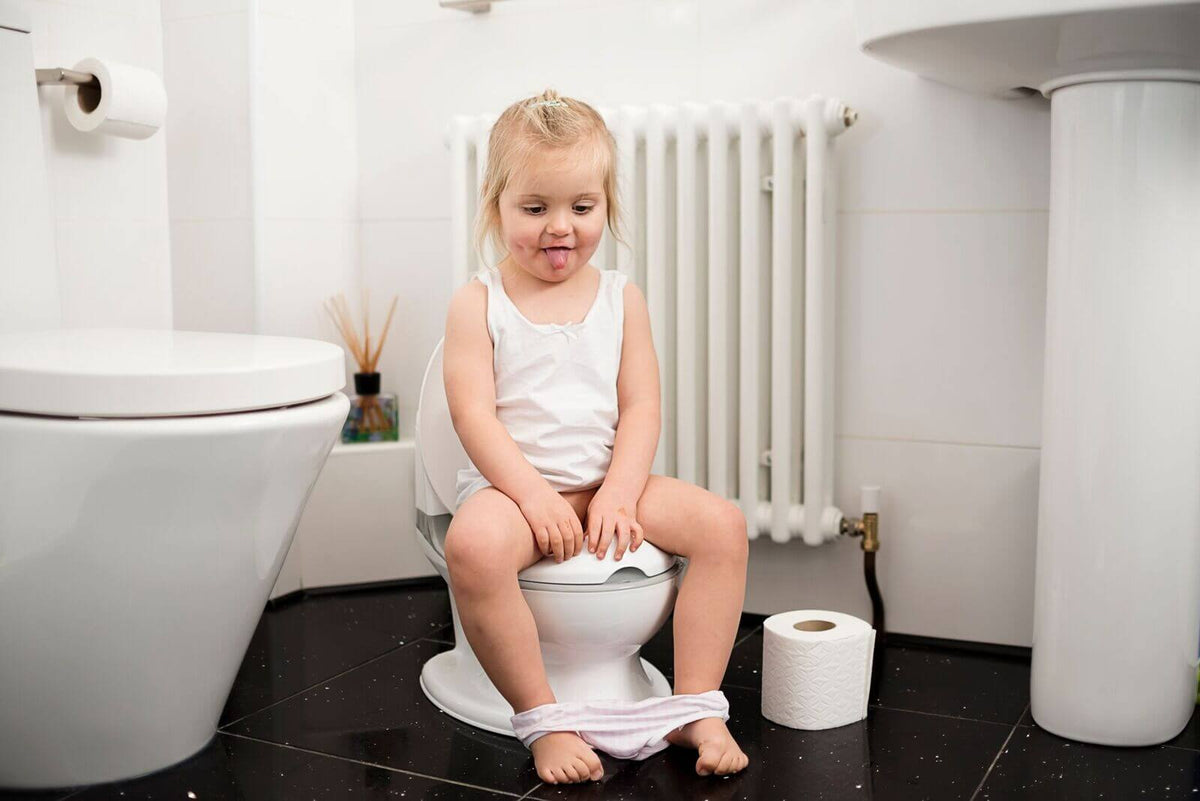 A girl utilising a Nuby potty in a bathroom.