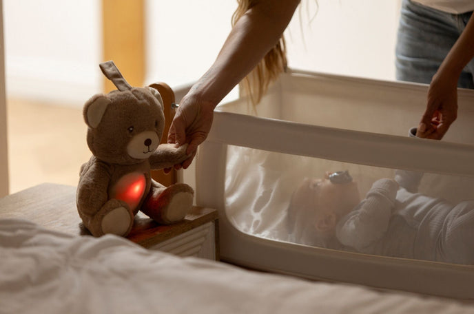 A Mother holding the Biscuit Bear sleeping aid next to their baby to help them sleep while in the bedroom.