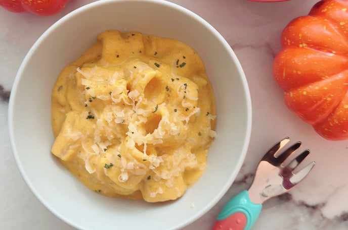 A white bowl with pumpkin pasta inside.