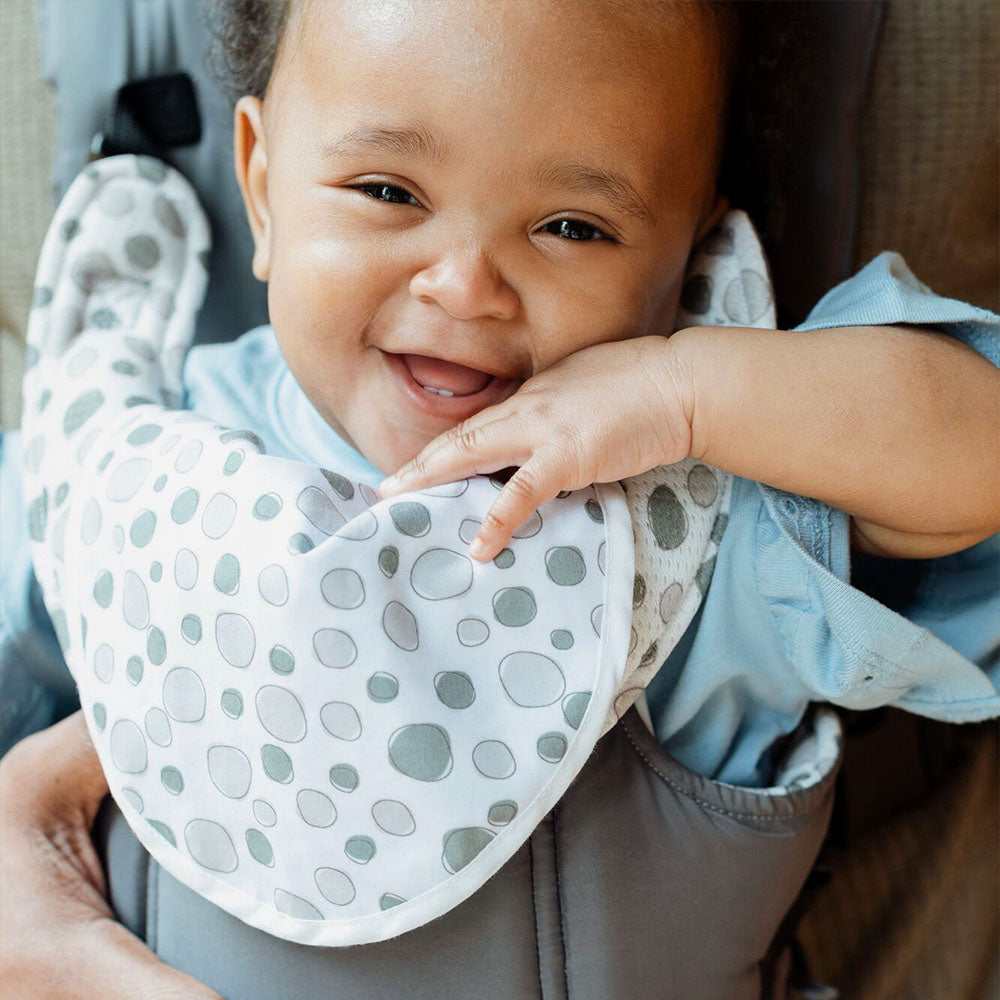 A close up of a baby that is smiling while sat inside the 2 in 1 Baby Carrier created by Nuby.