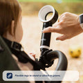 A hand attaches the Nuby UK Bladeless Fan with flexible legs to a stroller for a child. Text reads, Flexible legs let the Nuby UK Bladeless Fan stand or attach to prams.