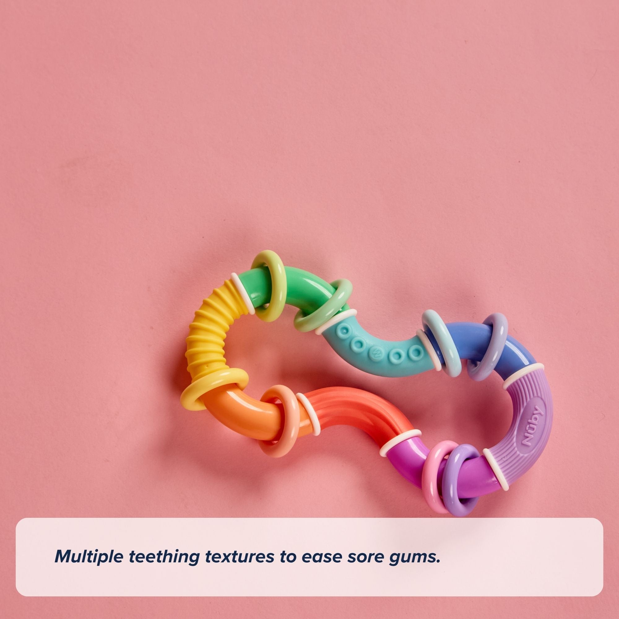 A vibrant, S-shaped Twista Rattle Teether with multiple textures rests on a pink background. In the corner, text reads: Multiple teething textures to soothe sore gums and provide comforting relief with this sensory toy.