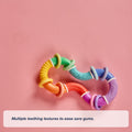 A vibrant, S-shaped Twista Rattle Teether with multiple textures rests on a pink background. In the corner, text reads: Multiple teething textures to soothe sore gums and provide comforting relief with this sensory toy.