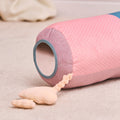 The Little Hops & Raindrops Tummy Pillow, featuring a soft blue and pink polka dot design, rests on a light carpet. It has a circular end opening with an attached plush heart-shaped toy for added fun.