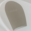 Close-up of the Nuby Sit Me Up Baby Baths interior, highlighting its gray non-slip backrest with the Nuby logo. Compact and ideal for bath time, small water droplets are visible on the white surface.