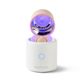 A white cylindrical RapidSoother Dummy & Pod with a pink rounded lid open, showing a glowing purple interior. It features a blue power button and has the RapidSoother logo on the front.