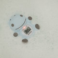 The Nuby Hippo Bath & Room Thermometer floats in soapy water, showing 39.5°C on its digital display with a red light indicator illuminated.