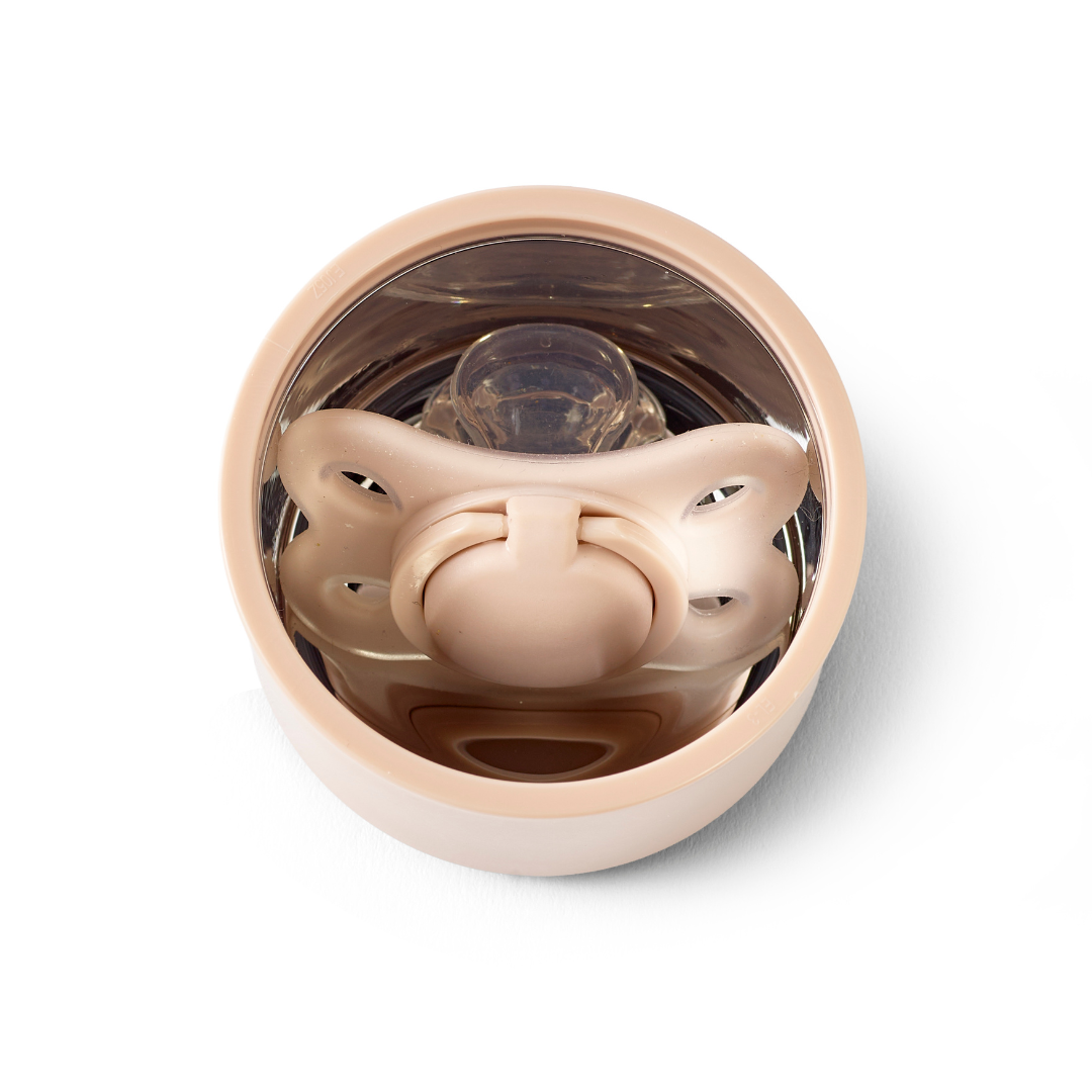 The RapidSoother Dummy & Pod, a beige baby pacifier in a round, clear storage case, is shown from above on a white background.