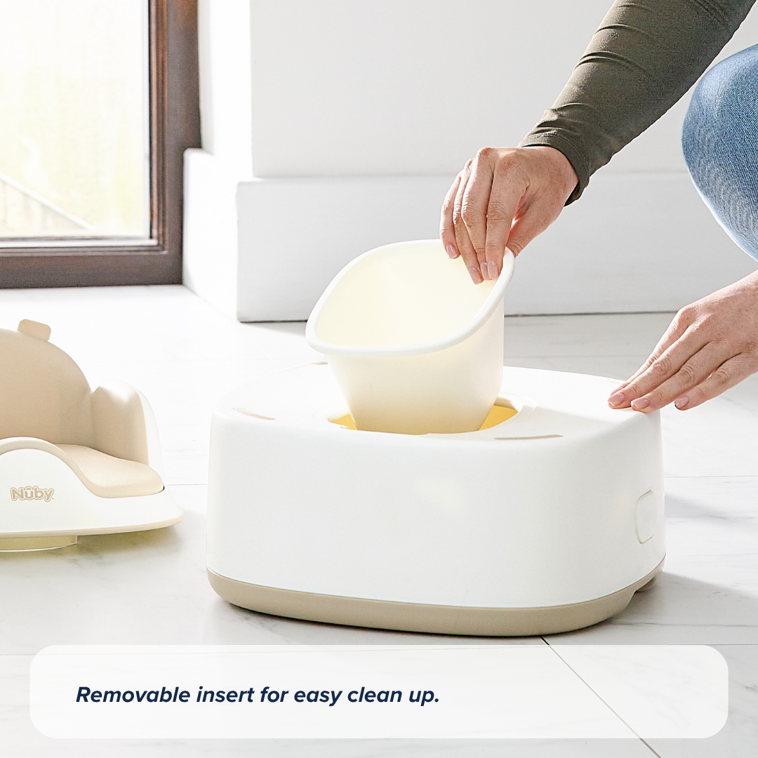 A person lifts a removable insert from the Gro Up 3 in 1 Potty in white and beige on a tiled floor, highlighting its removable insert for easy clean up—perfect for hassle-free potty training.