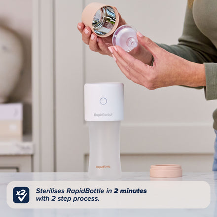 A person assembles a white RapidSterilise Plus UV Steriliser with beige lid, holding a bottle nipple and cap. Text: Sterilises bottles in 2 minutes with a 2-step process using RapidSterilise Plus.