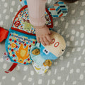 A baby reaching for the face of an animal that is included in the Teether book by Nuby.