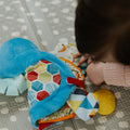 A baby playing with a teether book from Nuby.