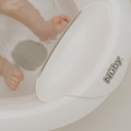 Close-up of a baby’s feet partially submerged in water inside the Nuby Sit Me Up Baby Bath. Only the lower legs and feet are visible.
