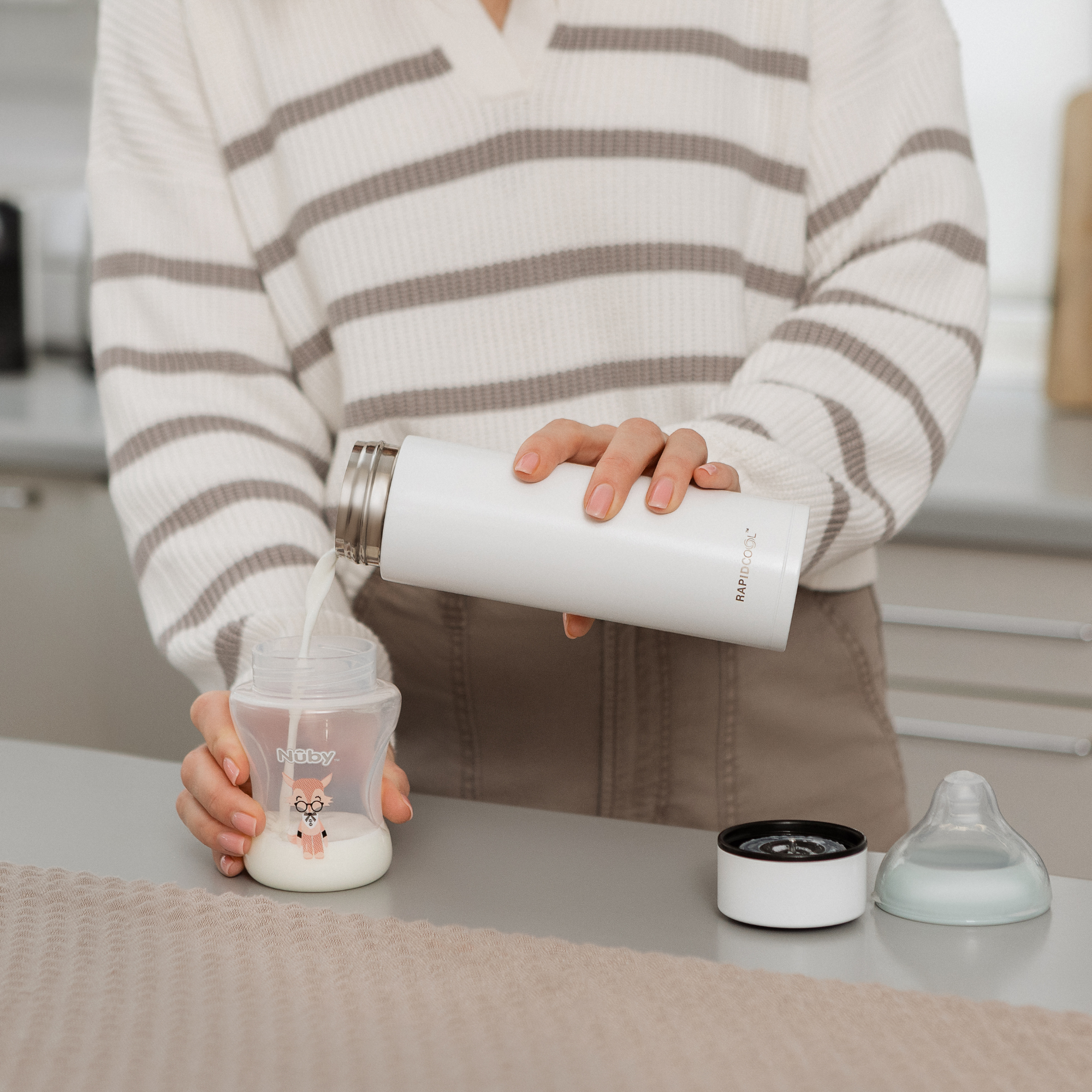 RapidCool Bottle Maker and UV Steriliser Bundle RapidCool Nuby UK, a woman pouring feed into a baby bottle.