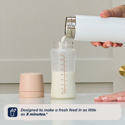 A person pours milk into a glass from the RapidBottle 2 Pack Glass Baby Bottles.