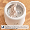 A RapidSoother 2-pack dummy is placed inside a white RapidSterilise+ device on a wooden surface, ready to be sterilized with UV light. Instructions are shown in a text box at the bottom.