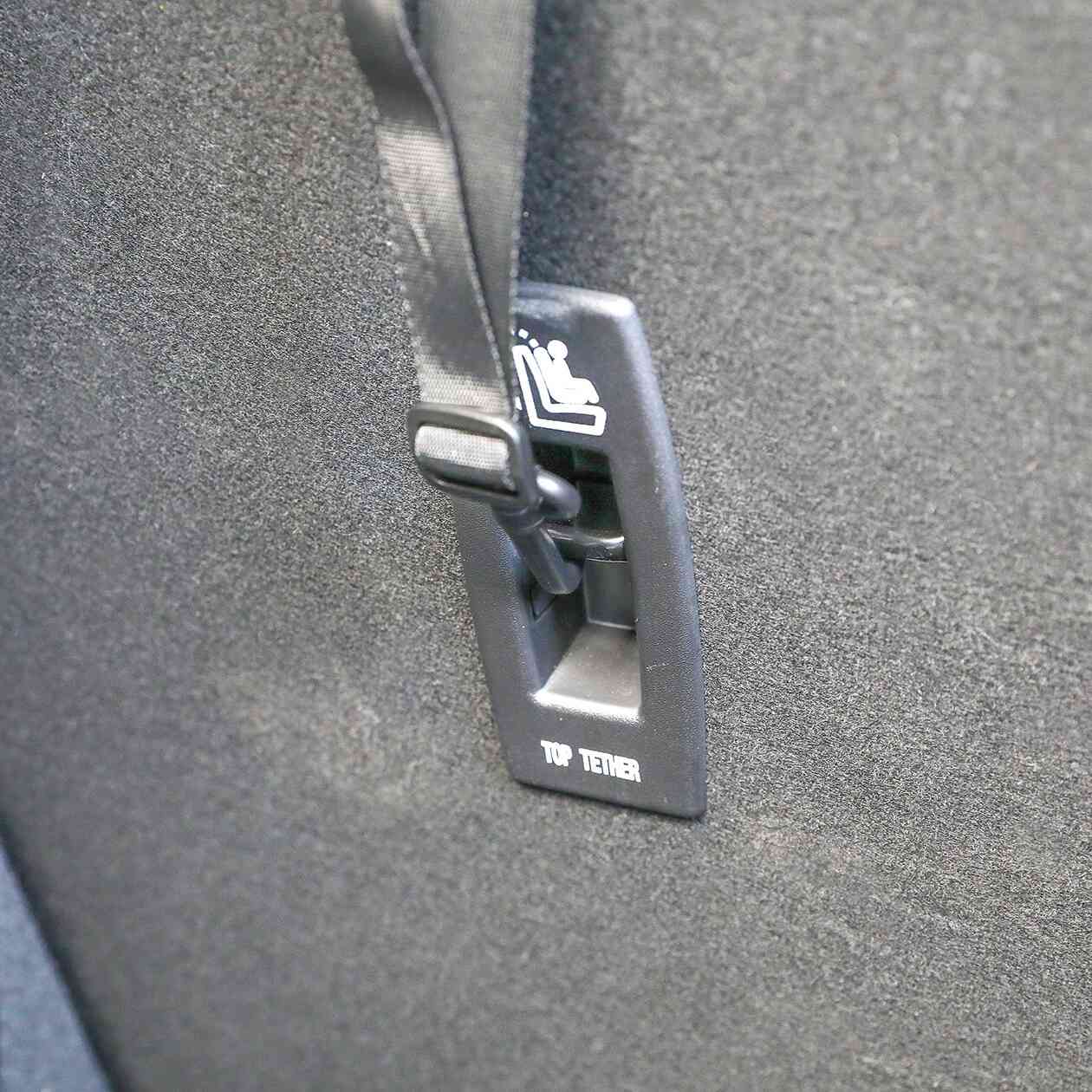 Close-up of a car seat’s top tether anchor with a strap in the labeled TOP TETHER slot, showing ideal placement for your shatter resistant Safe and Secure Baby Car Mirror.