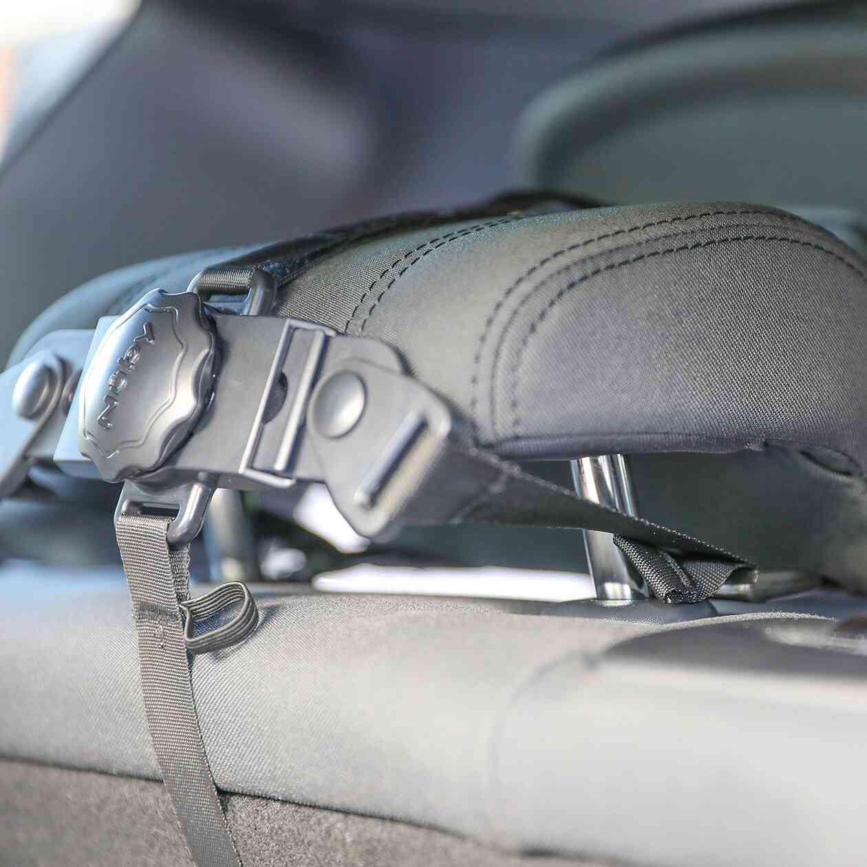 Close-up of a car seat headrest with a black adjustable strap and buckle fastened around it, designed to hold the Safe and Secure Baby Car Mirror, showing fabric details and the locking mechanism for shatter resistance.
