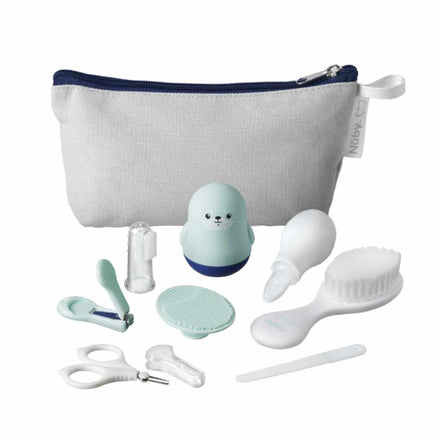 The Nuby Baby Healthcare and Grooming Kit includes a nail clipper, scissors, brush, silicone finger toothbrush, medicine dropper, nasal aspirator, silicone scrubber, seal-shaped item, and a white pouch—all organized neatly in front of the pouch.