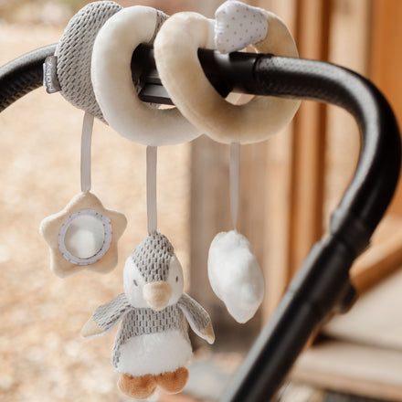 Nuby Penguin Activity Spiral Travel Pram Toy: Plush spiral attaches to stroller handle, featuring hanging star mirror, penguin, and cloud shapes for interactive fun.
