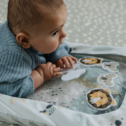A baby lying on their front on the Animal Adventures Tummy Time water mat.