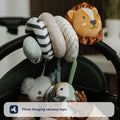 A baby reaches for three plush sensory toys—a lion, koala, and duck—from the Nuby UK Animal Adventures Playtime Set, hanging from a pram activity spiral on the stroller handle.