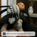 A baby relaxes in a stroller as the Nuby UK Animal Adventures Playtime Set—featuring a lion, koala, and bird—wraps around the pram bar for fun, on-the-go play. Text: “Wraps around pram bars for play time on-the-go.”.