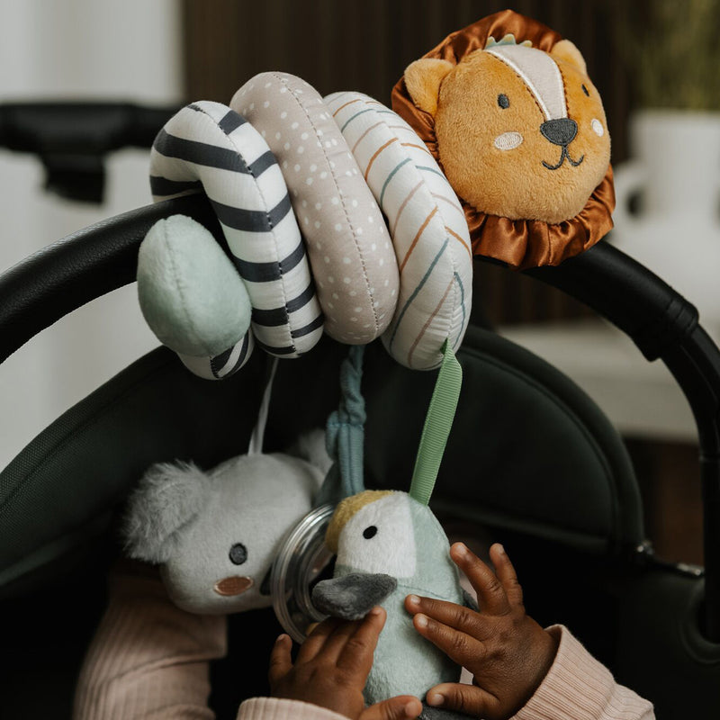 A baby reaches for lion, koala, and duck toys on the Animal Adventures Pram Spiral Activity Toy, each attached to a colorful striped and polka-dotted spiral designed for stroller sensory play.