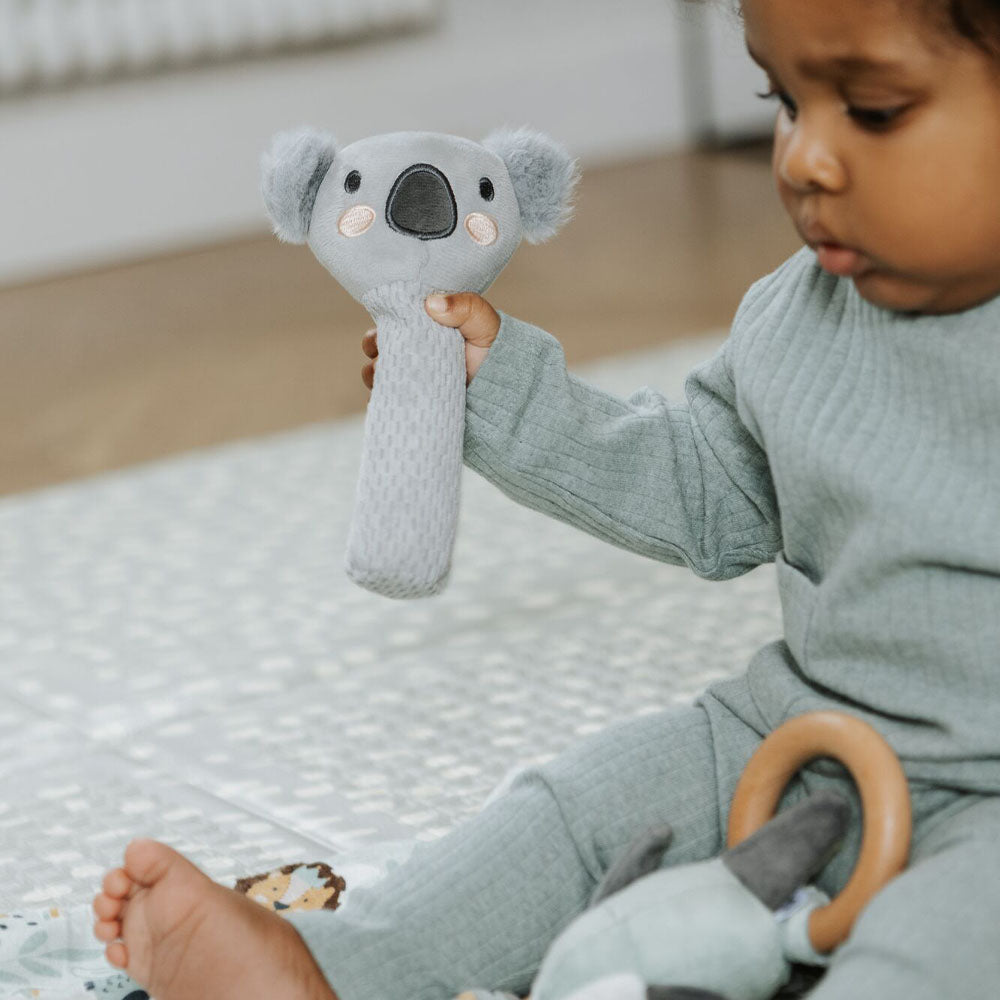 A baby holding the Koala from the Animal Adventures gift set by Nuby.