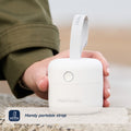 Someone holds the compact RapidSterilise UV Soother Steriliser with a looped strap outdoors by a stone surface. The image text says: Handy portable strap.
