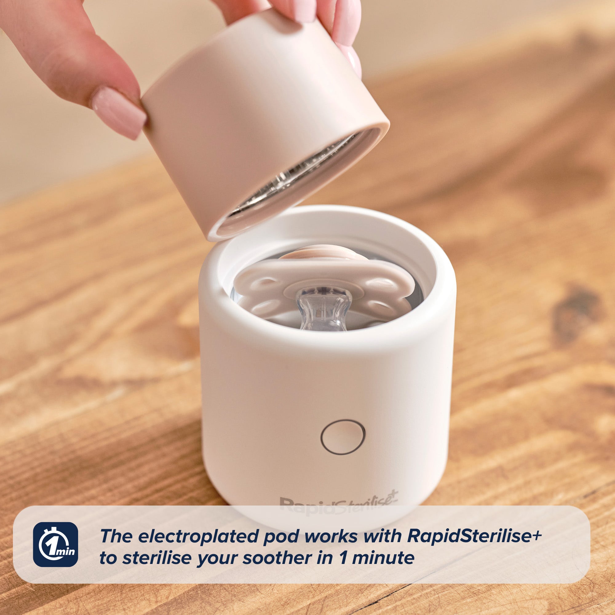 A hand lifts the lid off a compact, white RapidSoother Dummy & Pod with a dummy inside. Text overlay: The electroplated pod and RapidSterilise+ sterilise your dummy in 1 minute, with a 1-minute icon displayed.