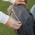 A woman's hands closing a zip that is part of the Baby Changing Backpack.