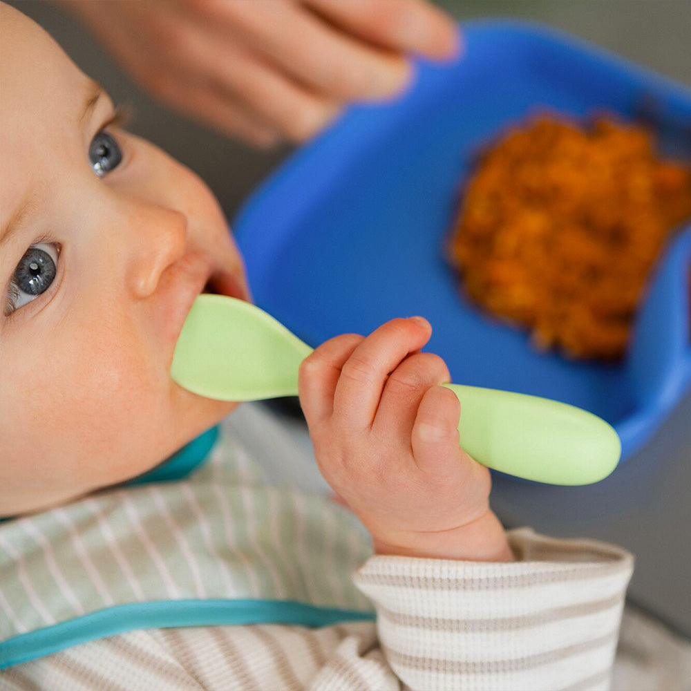 A baby holding the Brights cutlery to their mouths while they're eating.