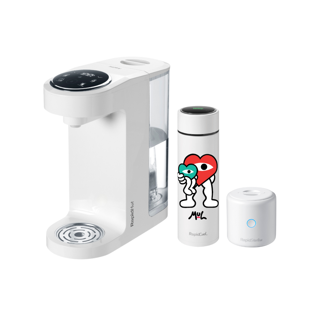 The Nuby UK Formula Making Set features a white, rapid-heating beverage maker with a clear water reservoir, smart lid, and a travel mug adorned with colorful cartoon hearts and abstract faces.