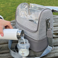 A photo of the RapidCool pouring feed into a sterilised cup next to the Portable UV Steriliser on a bench in the park.