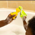 A green and yellow Dino Squirter bath toy being held up next to each other.