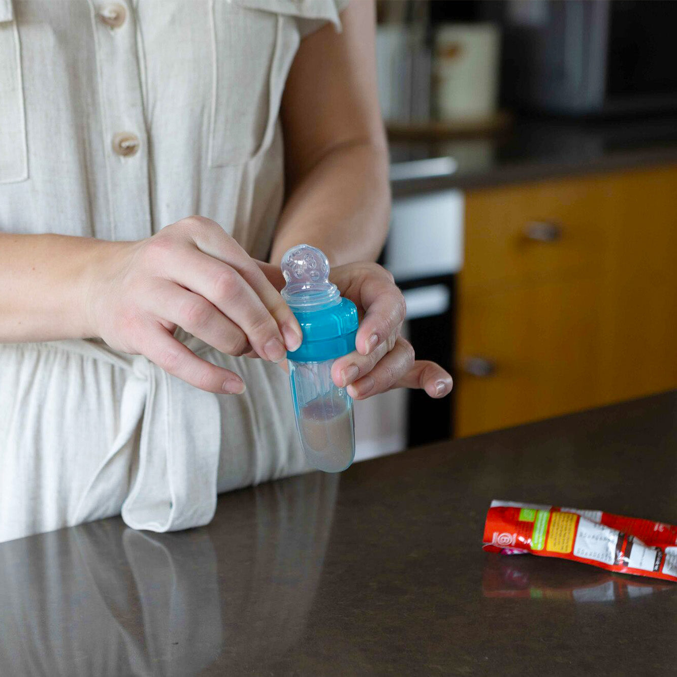 The EZ Squeez-ee being filed by a parent before they pass it to their baby.