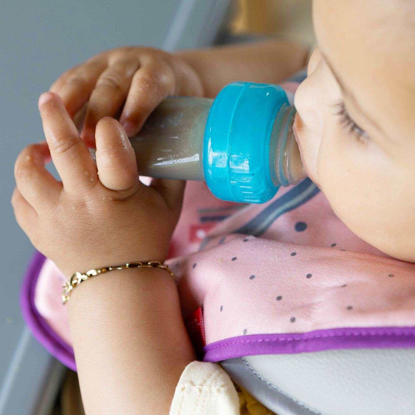 A baby eating baby food from their EZ Squeeze by Nuby.