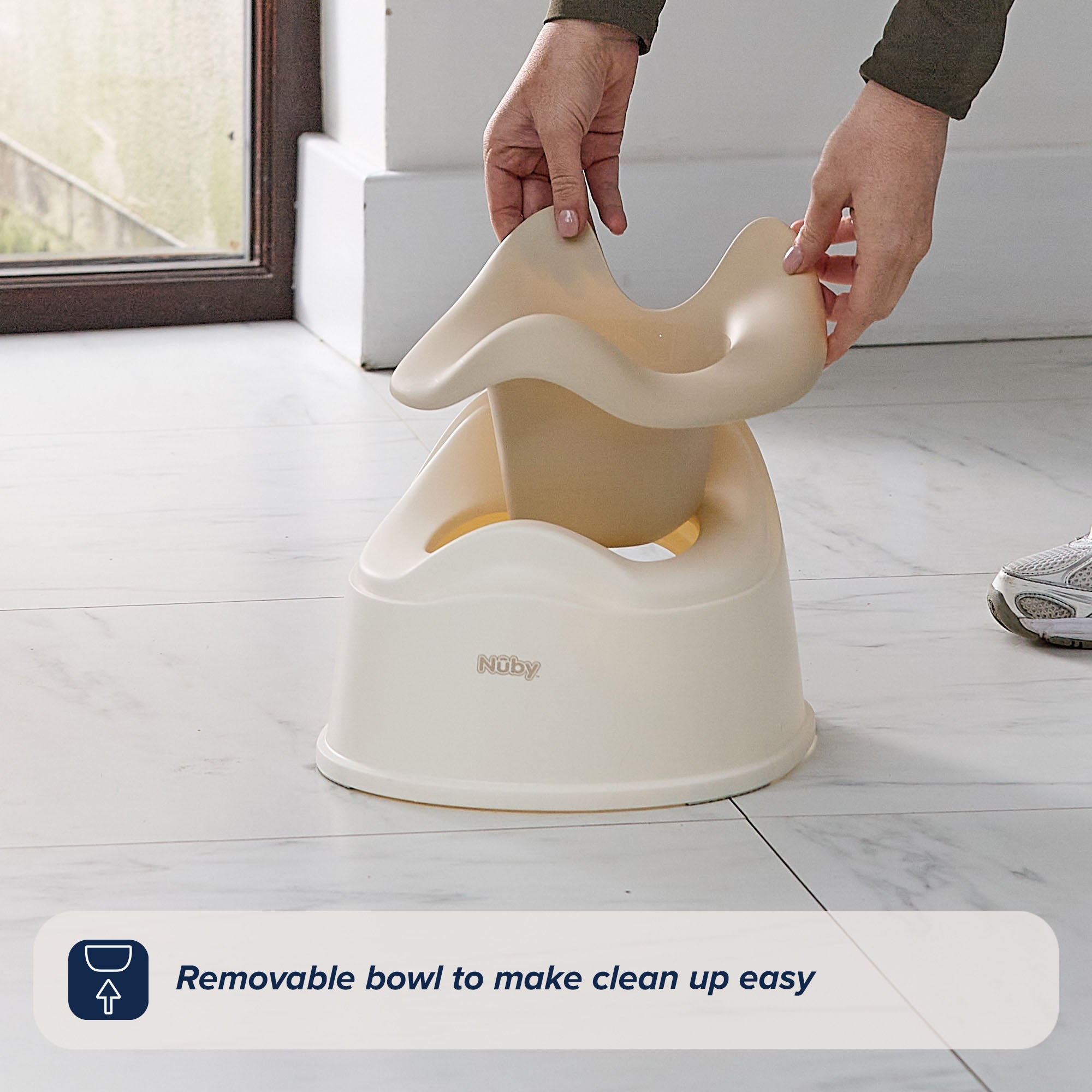 A person lifts the removable bowl from the Easy Clean Potty Beige on a tiled floor, with text reading, Removable insert to make potty training clean up easy.